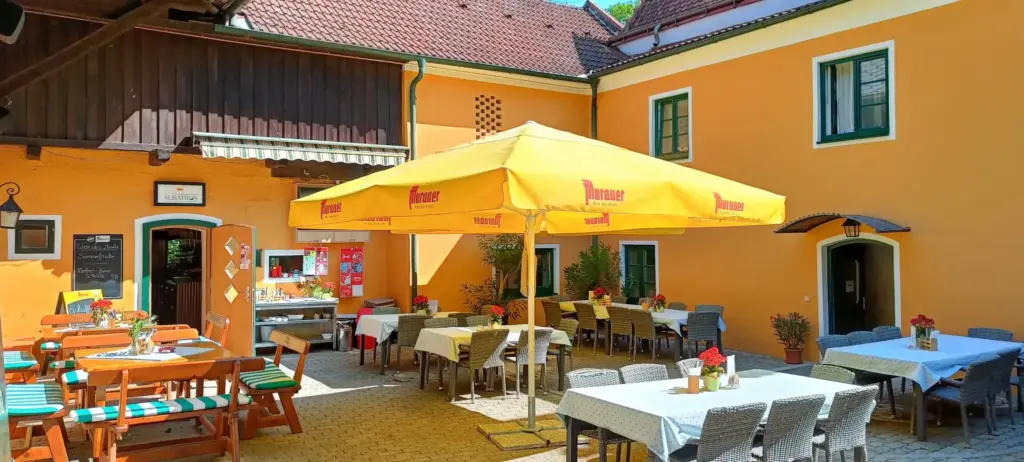 Innenhof unseres Historischen Clubhauses mit Tischen und Stühlen bei Strahlendem Sonnenschein.